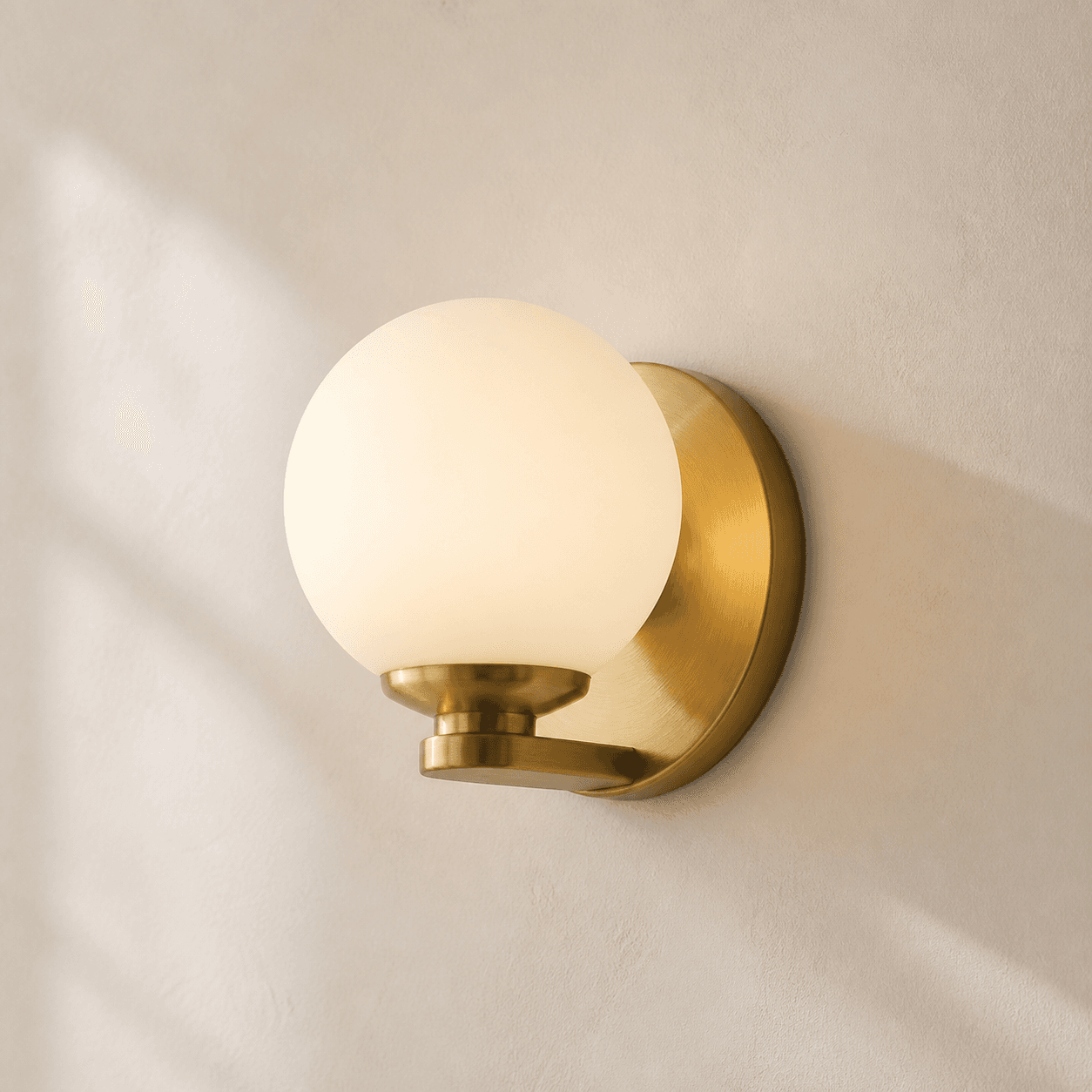 Frosted opal globe wall sconce with brushed brass backplate